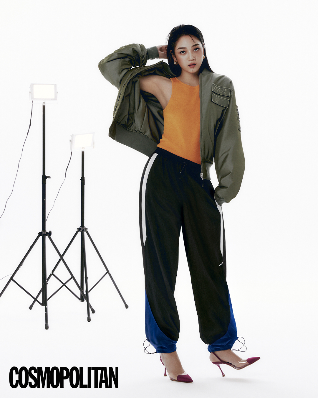 탈착 가능한 패치 장식의 카키 컬러 항공 재킷, 블루와 화이트 컬러 블록 라이프 젯에라 조거 팬츠는 팬암, 오렌지 컬러 니트톱은 샵 아모멘토, PVC 소재 핑크 힐은 73 아워즈, 골드 이어링은 스타일리스트 소장품.